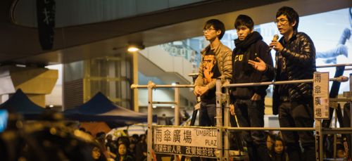 Alex Chow (right) addressing protesters during Hong Kong's Umbrella movement, alongside fellow student leaders Joshua Wong (left) and Lester Shum, December 2014 (Studio Incendo / Flickr)